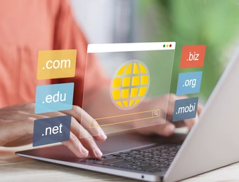 Person tippt am Laptop; bunte Domain-Tags (.com, .org, .net, .edu, .biz, .mobi) schweben vor einem Globus-Symbol.