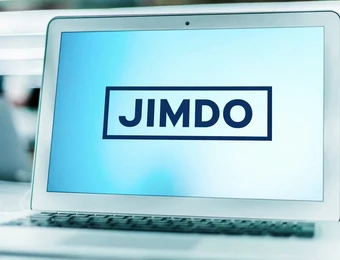 Aufgeklappter Laptop mit blauem Bildschirm; das Wort JIMDO steht in einem rechteckigen Rahmen.