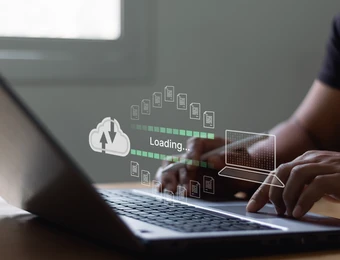 Person tippt auf Laptop; transparente Overlay-Grafik zeigt Ladebalken, Wolke mit Pfeil und App-Icons.