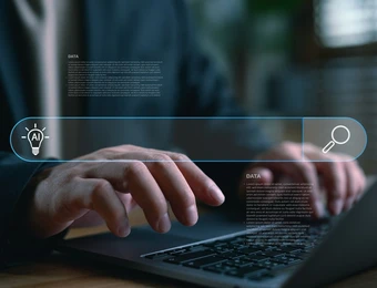 Person tippt auf Laptop; holografische blaue UI-Leiste mit Suchsymbol, AI-Icon und Textblöcken.