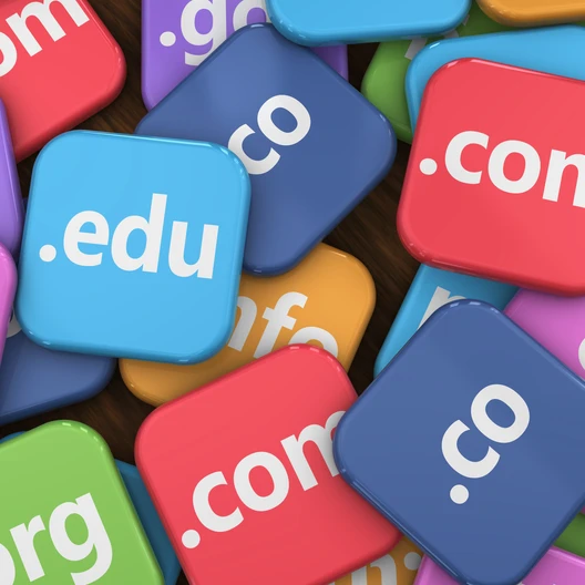 Viele bunte, quadratische Kacheln mit Domain-Endungen wie .com, .net, .org, .edu, in Rot, Blau, Pink und Grün.