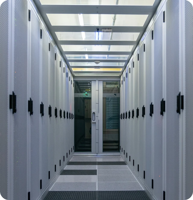 Langer Serverraum-Korridor mit weißen Serverracks links und rechts, Glas-Schiebetür am Ende.