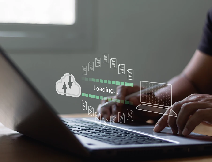 Person tippt auf Laptop; transparente Overlay-Grafik zeigt Ladebalken, Wolke mit Pfeil und App-Icons.
